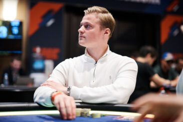 Casimir Seire istuu pokeripöydässä päällään valkoinen paita. Hän katsoo mietteliäänä sivulle ja nojaa kädellään pelipöytään.