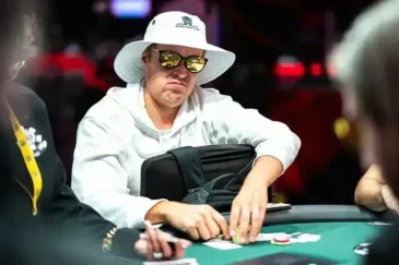 Eelis Pärssinen istuu pokeripöydässä. Hänellä on päässään valkoinen lierihattu. Silmillään Pärssisellä on tummat peililasit.