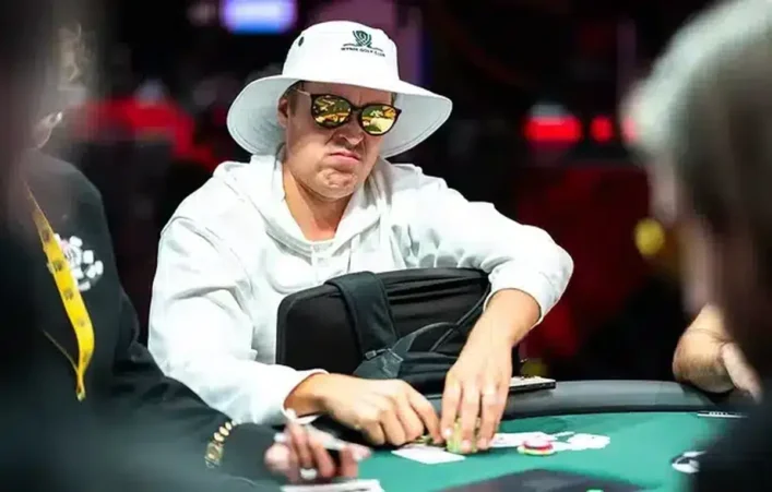 Eelis Pärssinen istuu pokeripöydässä. Hänellä on päässään valkoinen lierihattu. Silmillään Pärssisellä on tummat peililasit.