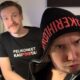 Mies huppu päässä ja duckface naamalla, takana toinen hymyilee paidassa jossa lukee "pelikoneet pois kaupoista"