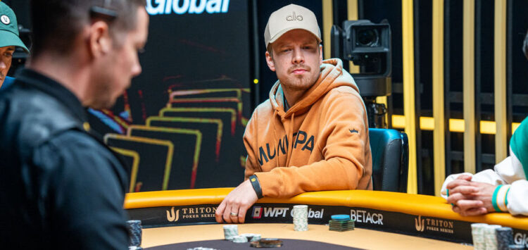 Joni Jouhkimainen istuu pokeripöydässä Tritonin turnaussarjassa. Hänellä on päässään vaalea lippis ja päällään oranssi huppari.