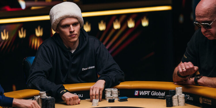 Ossi Ketola istuu pokeripöydän ääressä valkoinen turkishattu päässään ja pelaa pokeria.