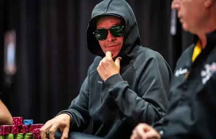 Eelis Pärssinen istuu pokeripöydässä. Hänellä on päällään huppari, jonka huppu on vedetty päähän ja silmillä on aurinkolasit.