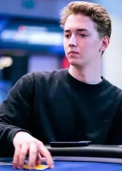 Luka Sorainen istuu pokeripöydässä musta kollari päällään