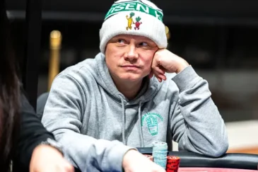Ilari Sahamies istuu pipo päässä pokeripöydässä ja hän nojaa nyrkkiinsä. Hänellä on harmaa huppari ja hieman mietteliäs ilme.