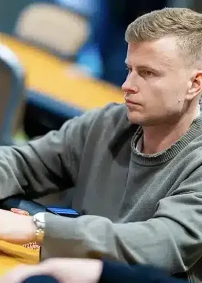 Jens Kyllönen istuu pokeripöydässä Tallinnan Chesterfield Poker Clubilla. Kyllösellä on vakava ilme kasvoillaan ja harmaa huppari