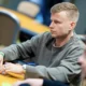 Jens Kyllönen istuu pokeripöydässä Tallinnan Chesterfield Poker Clubilla. Kyllösellä on vakava ilme kasvoillaan ja harmaa huppari