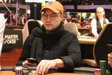 Matias Arosuo istuu pokeripöydässä. Hänellä on ihmettelevä ilme kasvoillaan ja hän pyörittelee pelimerkkejä käsissään.
