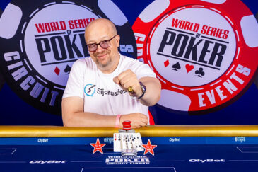 Aki Pyysing hymyilee voittajakuvassa Tallinnan WSOPC:ssa. Pyysingillä on sormessaan voittosormus ja päällään valkoinen t-paita.