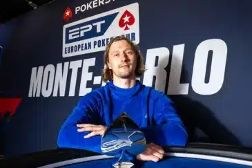 Aku Joentausta istuu Monte Carlon EPT -voittajakuvassa. Hänellä on päällään sininen paita ja edessään hopeinen voittopokaali.