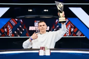 Aleksandr Shevliakov istuu EPT Monte Carlon jälkeen voittajakuvassa. Kädessään hänellä on voittopokaali ja edessään voittokäsi.