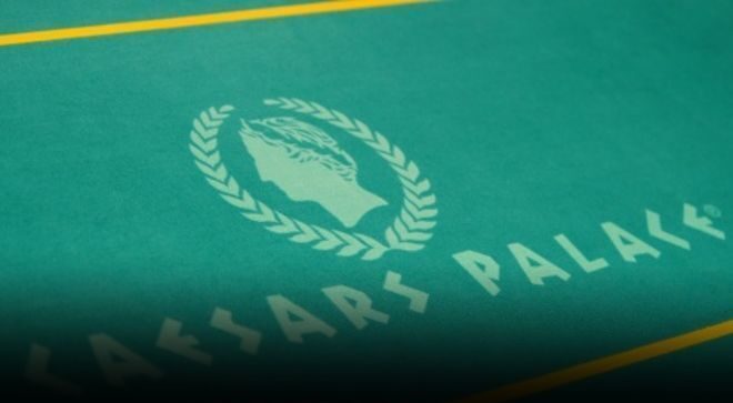 Pokeripöytä on vihreä ja siinä on Caesars Palacen logo, joka on kultaisen värinen ja sen ylä sekä alapuolella on keltainen viiva.