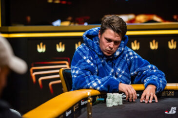 Eelis Pärssinen istuu pokeripöydässä Tritonin turnaussarjassa. Hänelle on päällään sininen huppari. Eeliksen ilme on vakava.