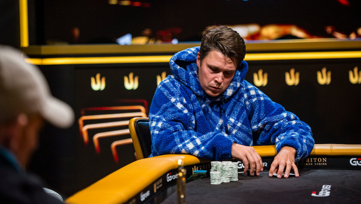 Eelis Pärssinen istuu pokeripöydässä Tritonin turnaussarjassa. Hänelle on päällään sininen huppari. Eeliksen ilme on vakava.