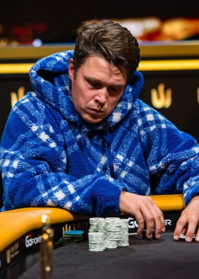Eelis Pärssinen istuu pokeripöydässä Tritonin turnaussarjassa. Hänelle on päällään sininen huppari. Eeliksen ilme on vakava.