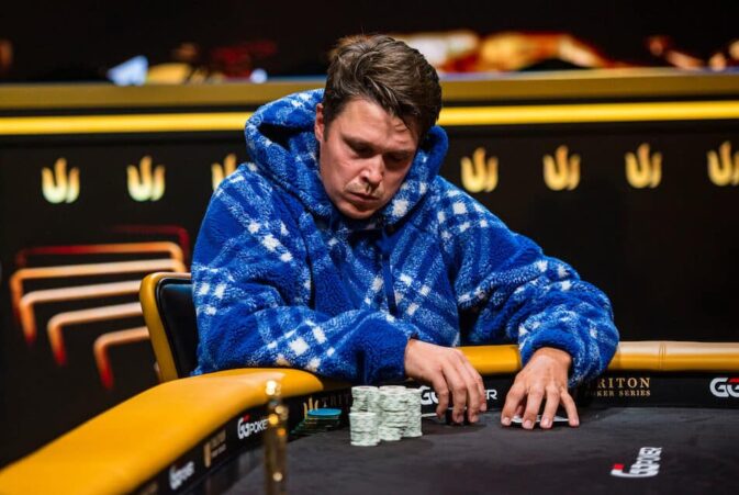 Eelis Pärssinen istuu pokeripöydässä Tritonin turnaussarjassa. Hänelle on päällään sininen huppari. Eeliksen ilme on vakava.