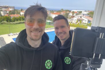 Antti Tiainen ja Veli-Matti "ReportAasi" Puumala ovat parvekkeella. Miehillä on päällä mustat nettipokeri.comin hupparit.