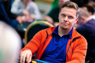 Joni Liimatta istuu pokeripöydässä. Hänellä on edessään pelimerkkejä. Jonilla on päällään punainen huppari, jonka alla t-paita