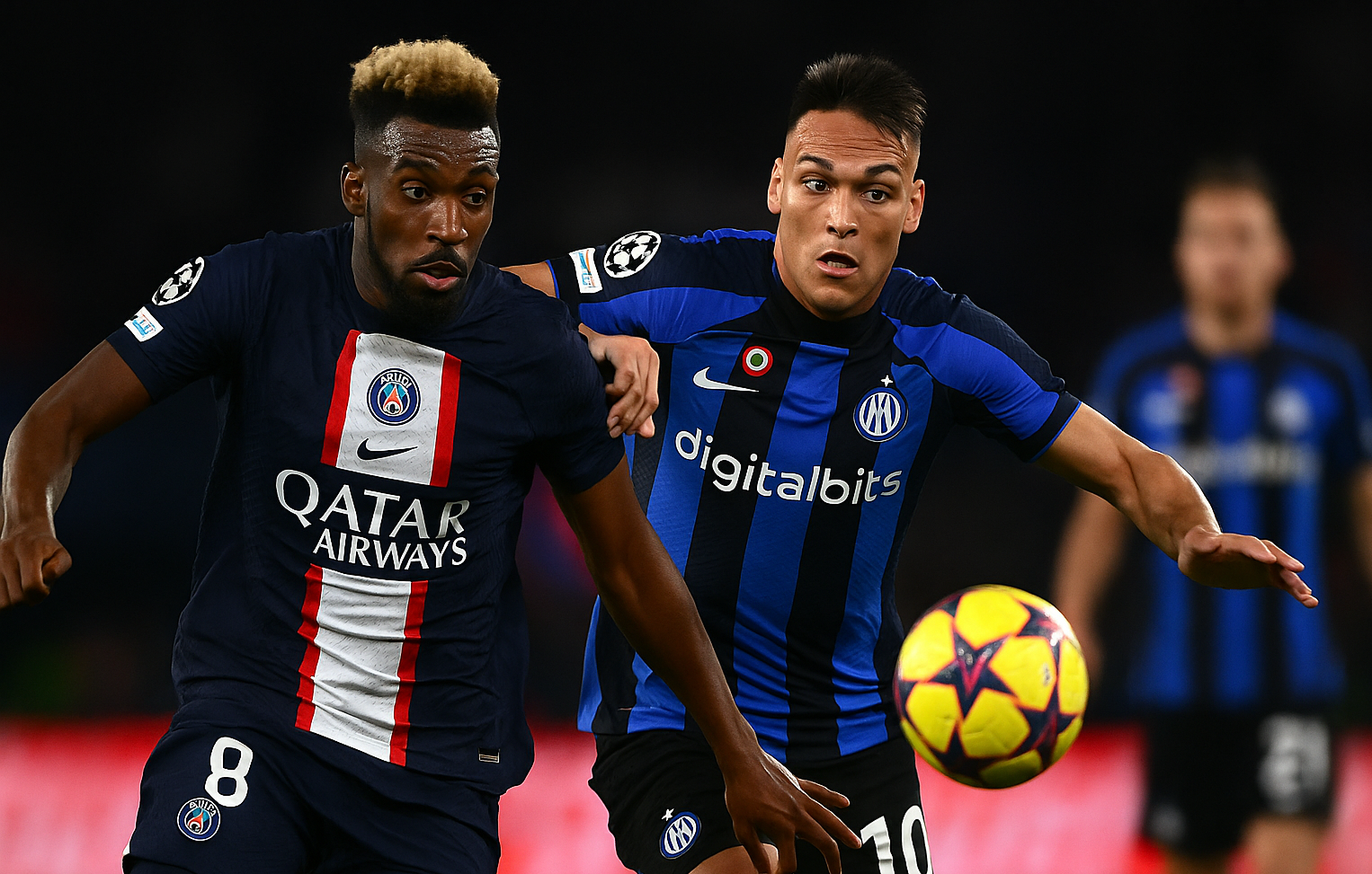 Inter Milanin ja PSG:n pelaajat taistelevat pallosta. Pallo on keltainen. Taustalla tilannetta seuraa Inter Milanin pelaaja.