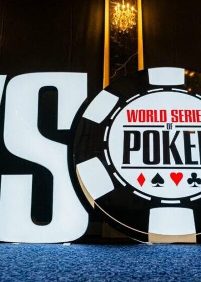 Etualalla World Series of Poker logo. Logo on sinisen alustan päällä. Taustalla on tummaa seinää. Tilaa valaisee seinävalot.