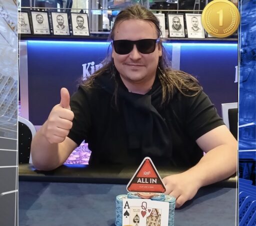 Pitkähiuksinen mies istuu pokeripöydässä. Hänellä on päällään musta t-paita sekä mustat aurinkolasit. Hän näyttää myös peukkua.