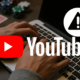 Etualalla on YouTuben logo sekä huomiomerkki. Taustalla näkyy ihmisen kädet, läppäri, pelikortit sekä pokerin pelimerkkejä.