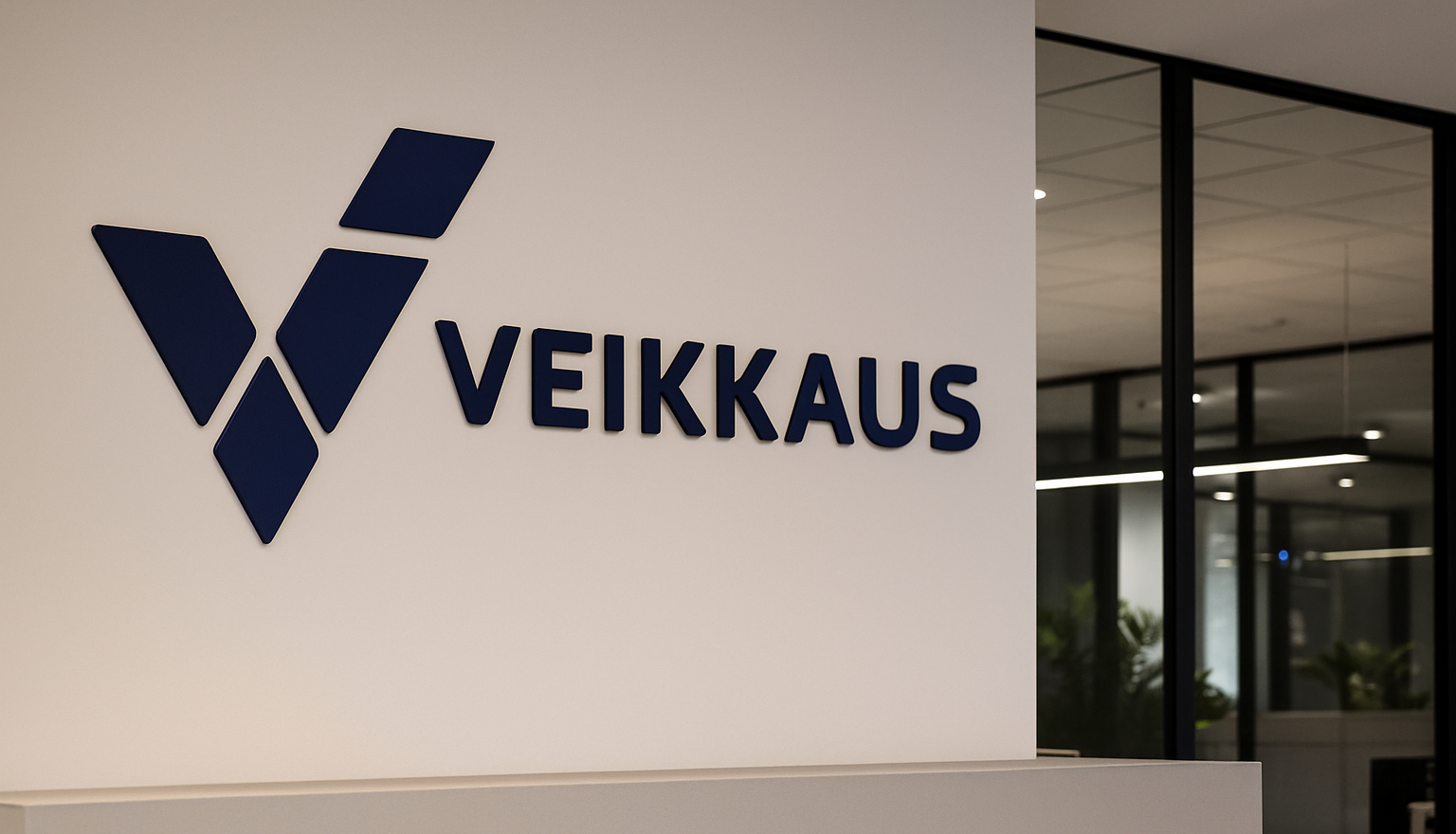 Valkoisella seinällä on sininen Veikkauksen logo ja lukee Veikkaus. Seinän vieressä on ikkunoita, jotka on rajattu karmeilla.