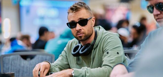 Mies istuu pokeripöydässä päällään vaaleanvihreä huppari päällään. Hänellä on kaulassaan kuulokkeet ja päässään aurinkolasit.