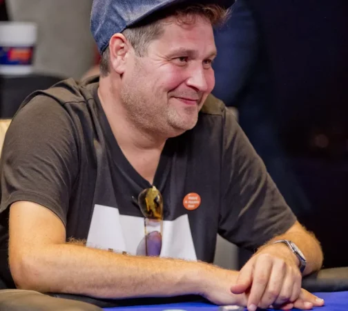 Jethro Rostedt istuu pokeripöydän ääressä hymyillen lippis päässään.