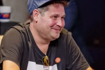 Jethro Rostedt istuu pokeripöydän ääressä hymyillen lippis päässään.