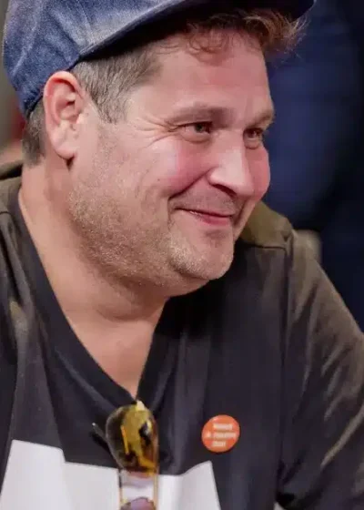 Jethro Rostedt istuu pokeripöydän ääressä hymyillen lippis päässään.