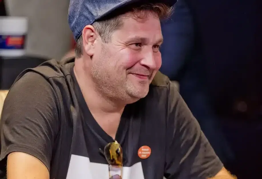 Jethro Rostedt istuu pokeripöydän ääressä hymyillen lippis päässään.