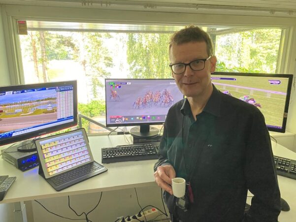 Jorma Vuoksenmaa kotitoimistollaan kahvikuppi kädessä mustassa kauluspaidassa.