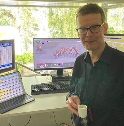 Jorma Vuoksenmaa kotitoimistollaan kahvikuppi kädessä mustassa kauluspaidassa.
