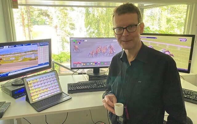 Jorma Vuoksenmaa kotitoimistollaan kahvikuppi kädessä mustassa kauluspaidassa.