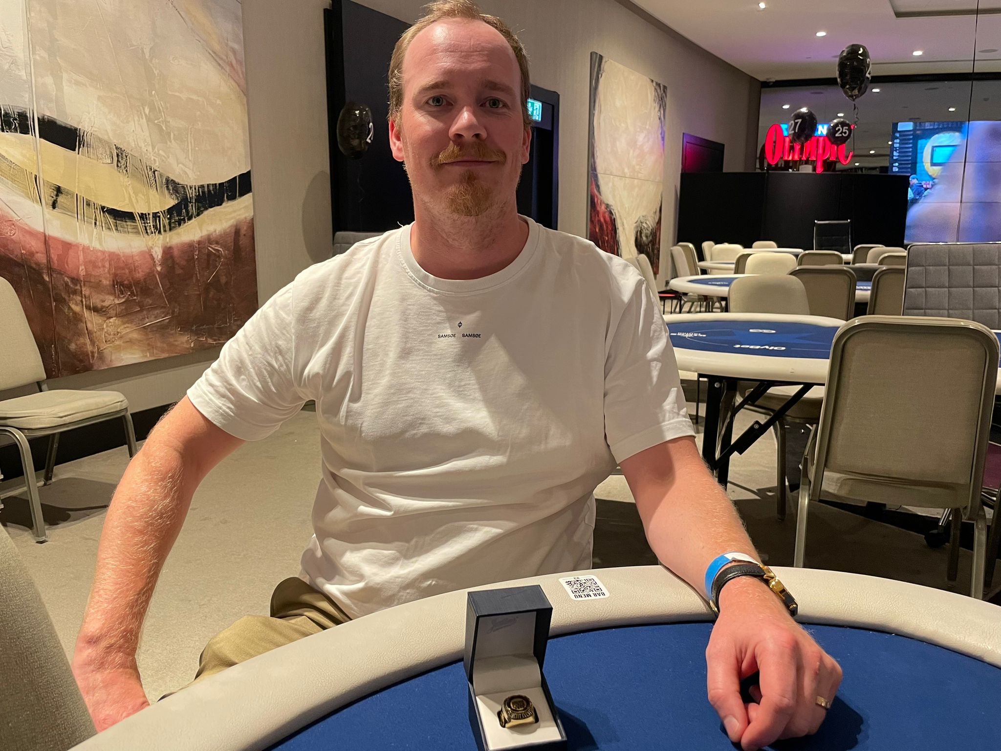 Jarkko Suokas istuu valkoisessa paidassaan pokeripöydän ääressä. Pöydällä on hänen juuri voittamansa WSOPC Tallinnan sormus.