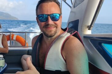 Tero Lipponen istuu veneessä meren aalloissa siniset aurinkolasit päässään pelastusliiveissä ja näyttää peukkua.