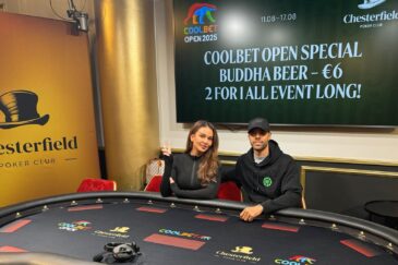 Nainen ja mies istuvat pokeripöydän ääressä, taustalla on televisio näyttö ja valkoista ja keltaista