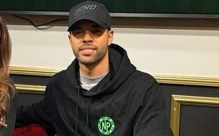 Nainen ja mies istuvat pokeripöydän ääressä, taustalla on televisio näyttö ja valkoista ja keltaista