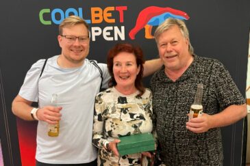 Kuvassa Ville Hakala perheineen seisoo rivissä äitinsä ja isänsä kanssa Coolbet Open plakaatin edessä. Äiti Päivi pitää kädessään vihreää laatikkoa.