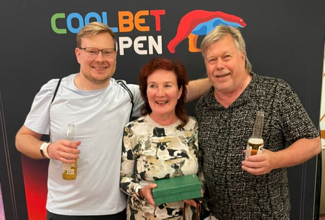 Kuvassa Ville Hakala perheineen seisoo rivissä äitinsä ja isänsä kanssa Coolbet Open plakaatin edessä. Äiti Päivi pitää kädessään vihreää laatikkoa.