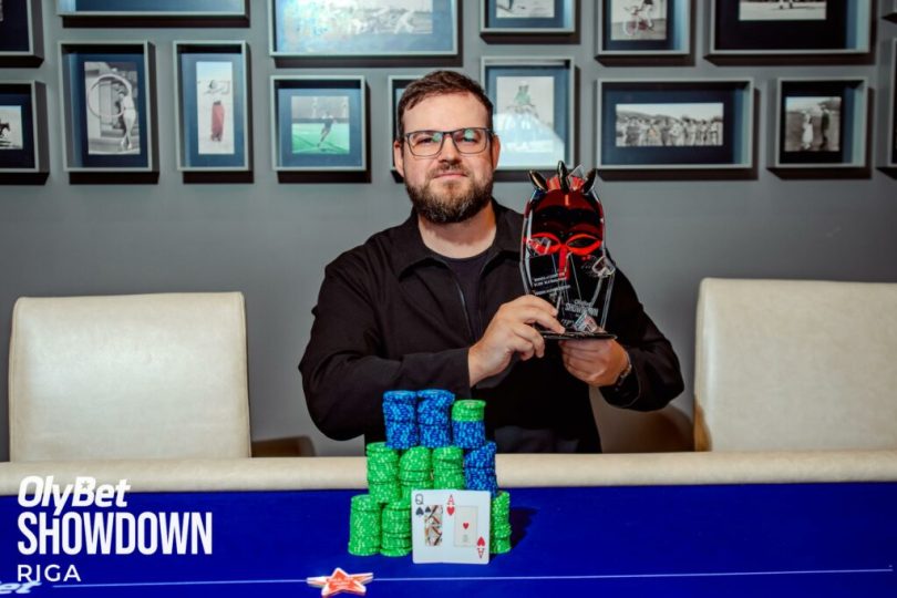 Mies poseeraa pikaalin kanssa pokeripöydän takana.