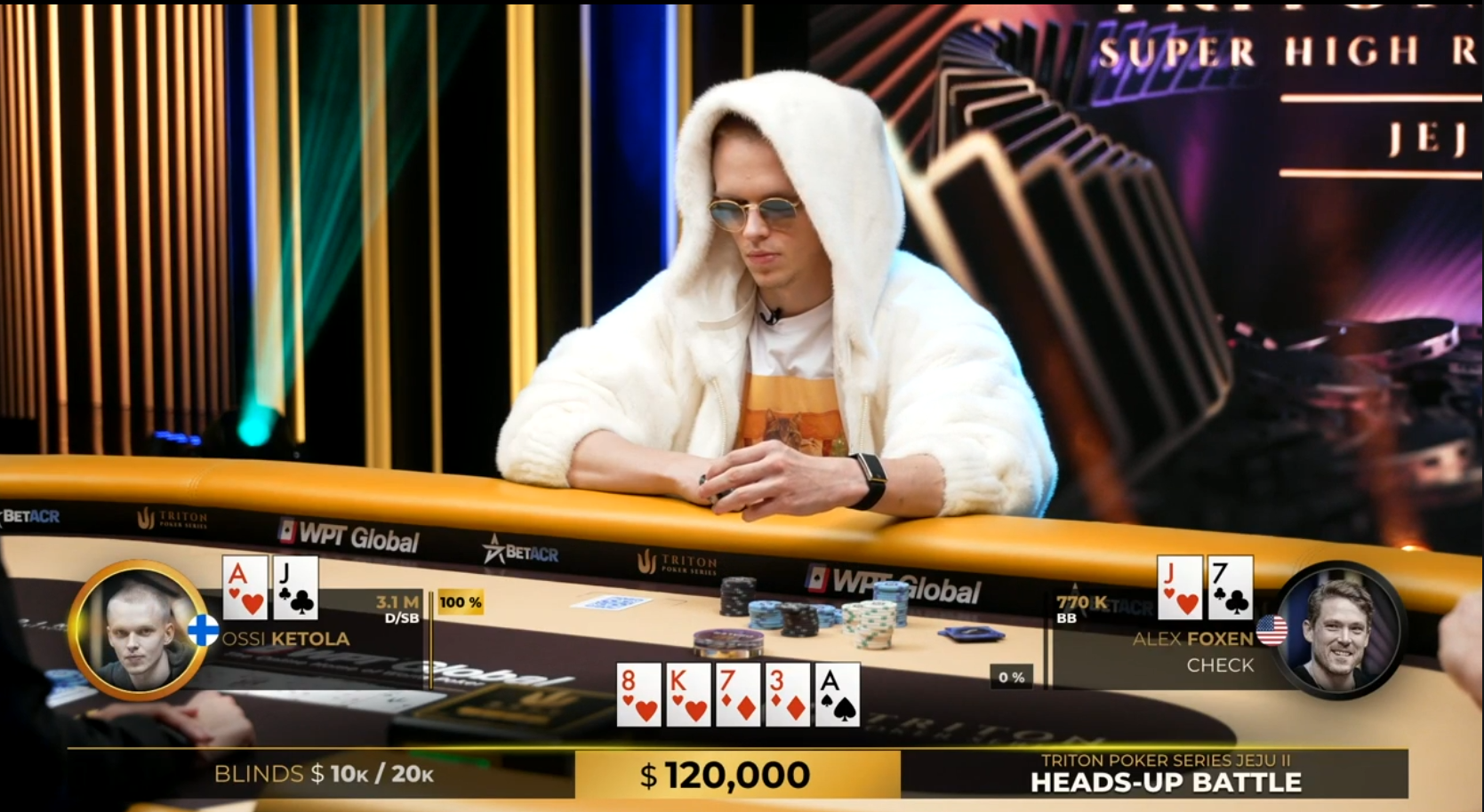 Mies istuu pokeripöydän äärellä valkoisessa hupparissa. Miehellä on päässään pyöreät auronkolasit ja edessään pelimerkkejä.