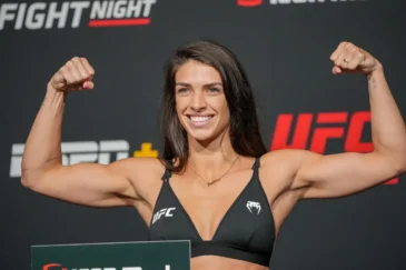 UFC-ottelija Mackenzie Dern näyttelee hauiksiaan UFC-valokuvausseinän edessä