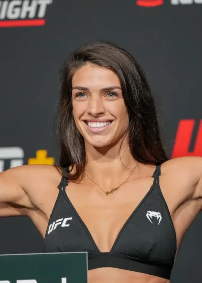 UFC-ottelija Mackenzie Dern näyttelee hauiksiaan UFC-valokuvausseinän edessä