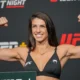 UFC-ottelija Mackenzie Dern näyttelee hauiksiaan UFC-valokuvausseinän edessä