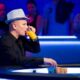 Ilaei Sahamies istuu sinisävyisessä pokeripöydässä hattu päässään, juoden lasista appelsiinimehua