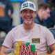 Kuvassa on yhdysvaltalainen pokeriammattilainen Chance Kornuth, joka on vangittu iloiseen ja rentoon hetkeen kesken turnauksen. Hän nauraa leveästi ja vapautuneesti kameralle. Kornuthilla on yllään vaalea t-paita ja valkoinen lippalakki, jossa lukee "SO HI". Hänen edessään vihreällä pelipöydällä on valtava pino erivärisiä pelimerkkejä, ja hänen paitaansa on kiinnitetty keltainen "CHIP LEADER" -merkki, mikä osoittaa hänen olevan turnauksen johdossa. Kuva on täynnä positiivista energiaa ja itseluottamusta, ja sen on ottanut valokuvaaja Hayley Hochstetler.