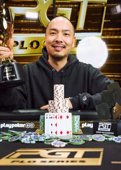 Kuvassa on iloisesti hymyilevä, kaljuuntuva mies, joka juhlii voittoaan PokerGO Tour (PGT) -turnauksessa. Hänellä on yllään musta huppari, ja hän pitelee ylpeänä toisessa kädessään suurta kultaista voittopokaalia. Hänen edessään mustalla pelipöydällä on korkea pino pelimerkkejä, joiden eteen on aseteltu voittokäsi: neljä ässää. Pöydällä on myös useita muita pienempiä PGT-palkintoja, kuten "Event #8 Champion" -laatta. Taustalla loistaa suuri, kulta-musta digitaalinen näyttö, jossa näkyy PGT-logo ja teksti "PLO SERIES". Kuva on täynnä tyytyväisyyttä ja menestyksen tuntua.
