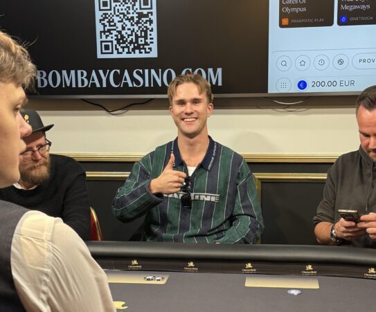 Joni "Stagala" Takala istuu pokeripöydässä kruunu päässään ja hymyilee kameralla peukaloa näyttäen.